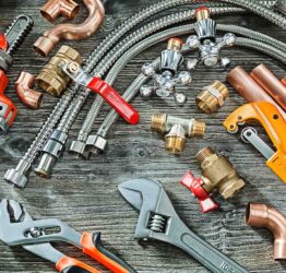 plumbing concept big set of piping accessories monkey and plumb adjustable wrenches copper brass fittings pipe cutter on vintage wood background